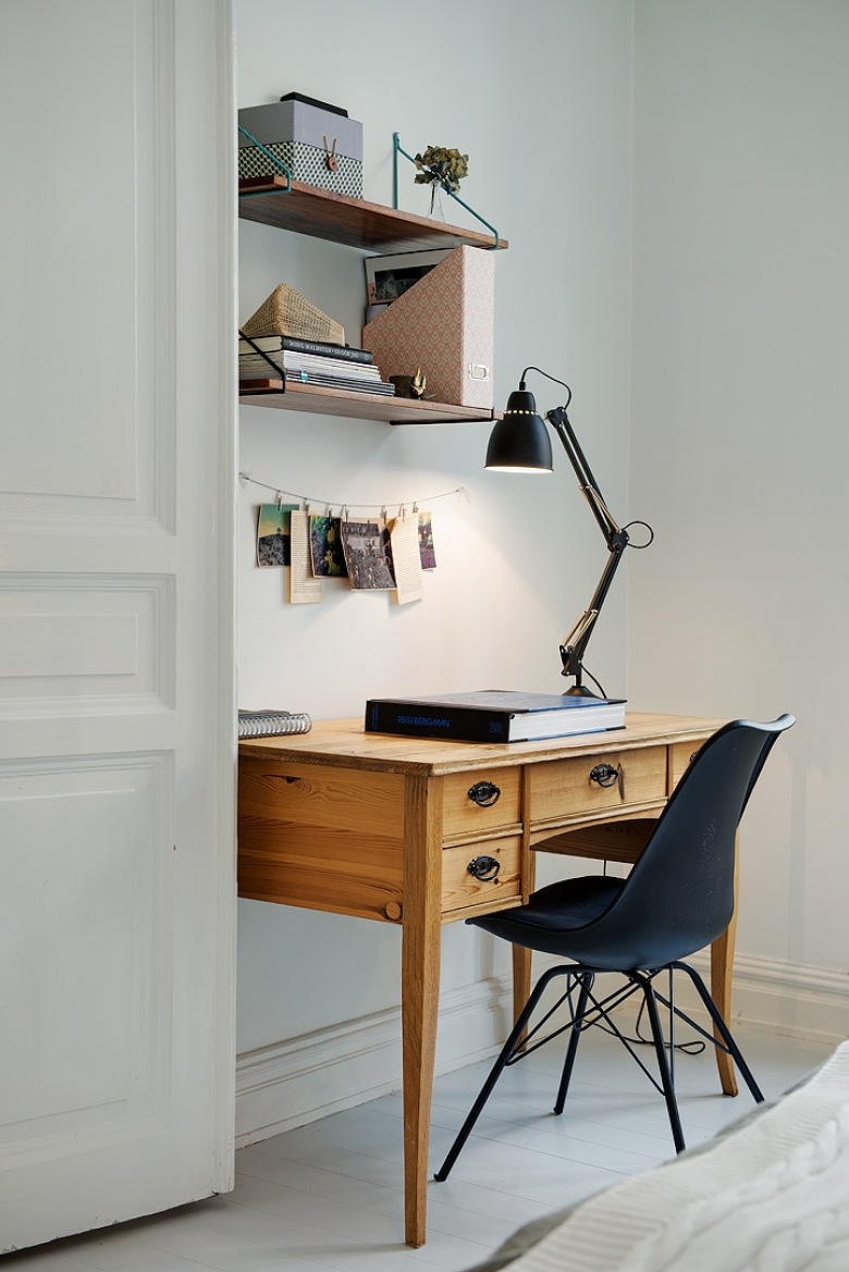 Drewniane miodowe biurko z wiszącymi pólkami na białej scianie w aranżacji mieszkania,czarne krzesło na krzyżakach i czarna lampa biurkowa z przegubami (26137)