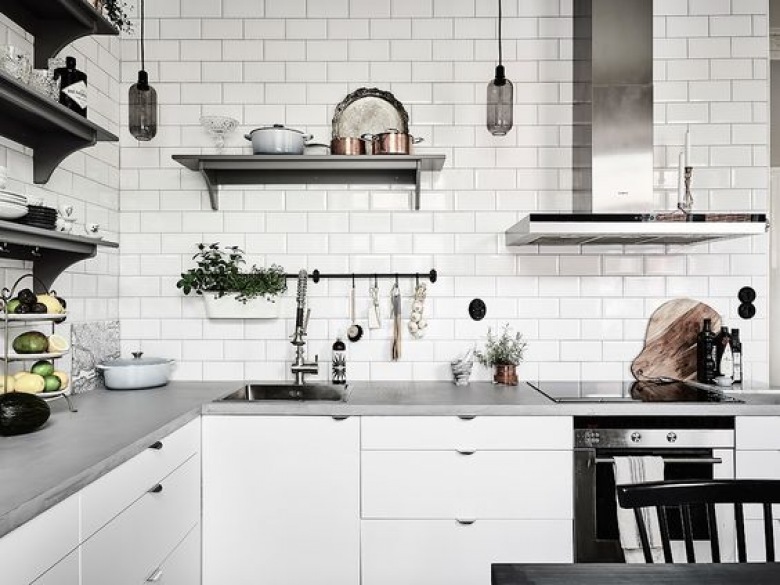 W białej kuchni zastosowano czarne dodatki, które przełamują spokojną paletę barw. Prostokątne kafle na ścianie wnoszą do wnętrza tradycyjny...