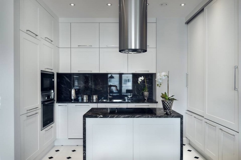 W kuchni dominuje biel przełamana nasyconymi czernią elementami z połyskiem. Gładkie fronty szafek kuchennych kojarzą się z minimalizmem stylu nowoczesnego. Wnętrze prezentuje się elegancko i schludnie, a podłoga z lekkim wzorem subtelnie uzupełnia...