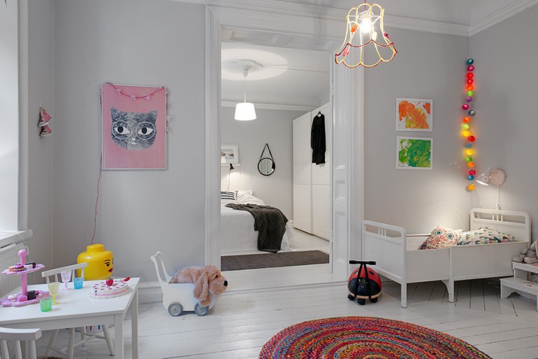 Pokój dziecięcy z białym łóżeczkiem,dzierganym okrągłym dywanem i dekoracyjnym oświetleniem z kolorowych kul (21617)