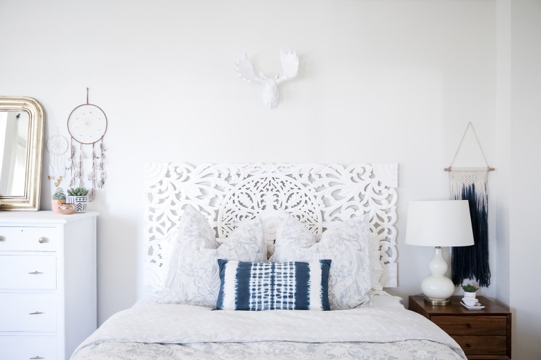 Dekoracyjne wezgłowie łóżka, a także inne delikatne białe dekoracje (głowa łosia na ścianie, wysoka komódka, lampa)...