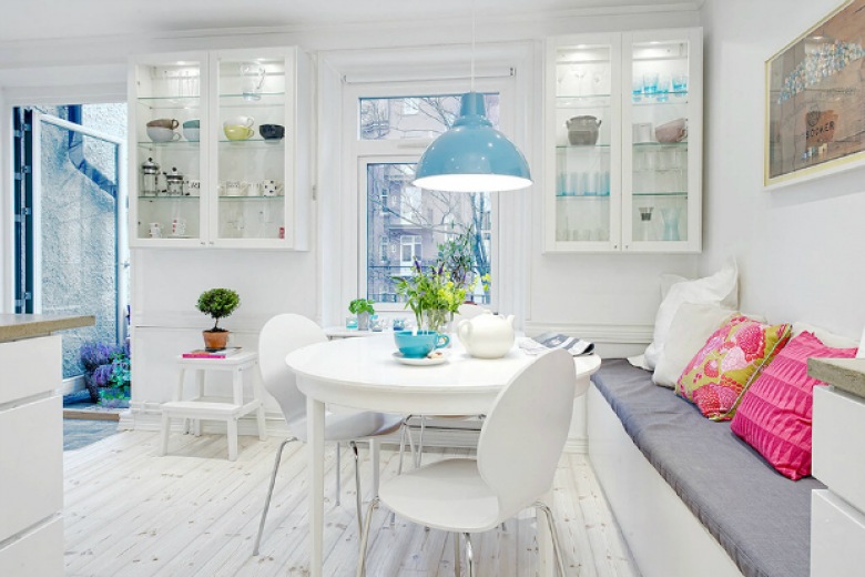 Wiszące białe witrynki, okrągły stół i ławka z poduszkami w skandynawskiej jadalni z niebieską lampą (22024)