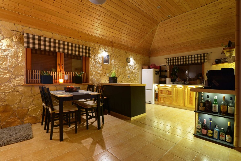 Drewniany sufit razem z kamienną ścianą podkreślają naturalny klimat domu. Jadalnia z kuchnią są dość...