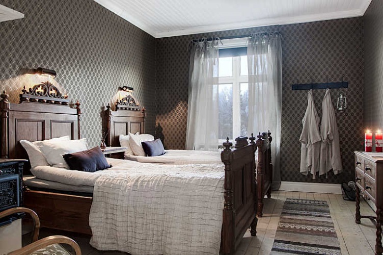 Stylowe rzeźbione łóżka z drewna w skandynawskiej sypialni z podłogą z surowych desek i tkanym dywanikiem (27639)