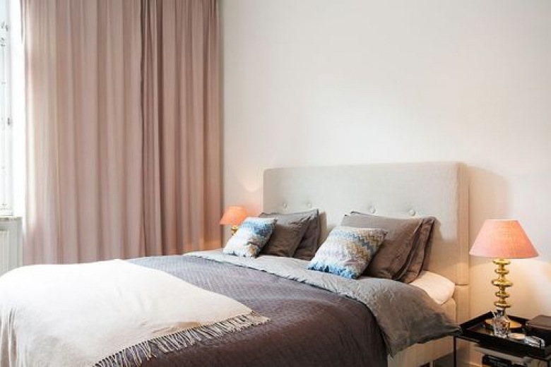 Biało-beżowa sypialnia skandynawska z poduszkami na łóżku z wzorem kolorowego szewronu (25424)