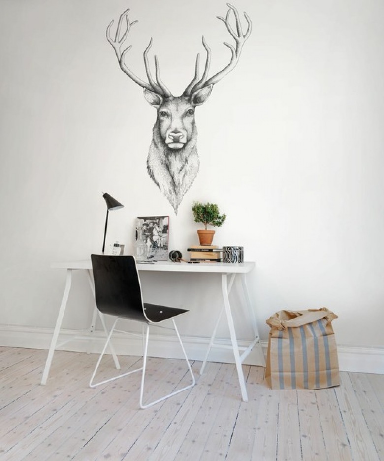 Prostą skandynawską aranżację pokoju biurowego urozmaica duża dekoracja na ścianie. Motyw jelenia świetnie wpisuje się w styl wnętrza i zdobi...