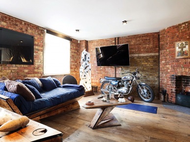 Oryginalny salon z motocyklem, dizjnerską sofą z drewna i szafirową tapicerką i ścianami z czerwonych cegieł (23698)