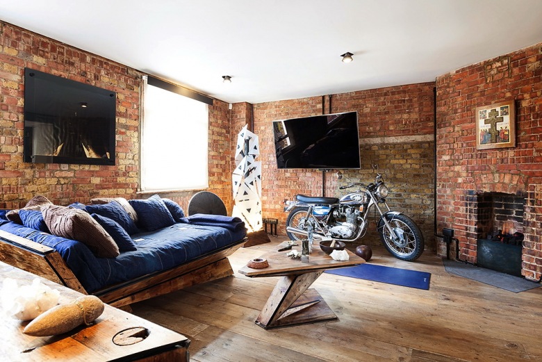 Oryginalny salon z motocyklem, dizjnerską sofą z drewna i szafirową tapicerką i ścianami z czerwonych cegieł (23698)
