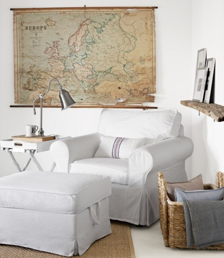Dekoracyjna mapa Europy, biały fotel  i drewniana półka w aranżacji salonu (28680)