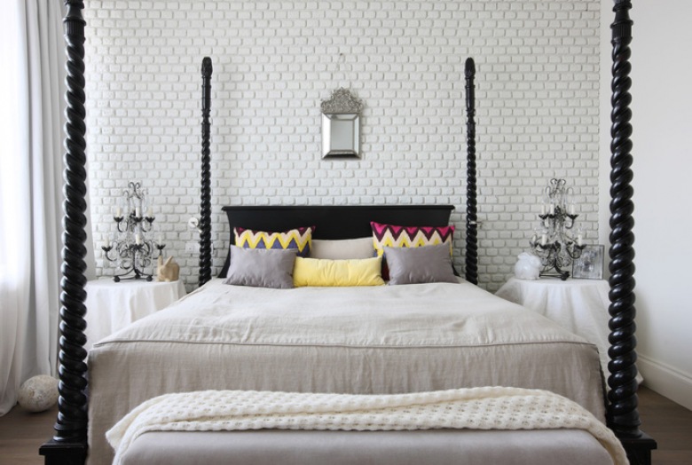 Biała cegła na ścianie w sypialni ze stylowym drewnianym łóżkiem,kolorowymi poduszkami w zygzaki i stylowymi świecznikami lampami na stolikach (27060)
