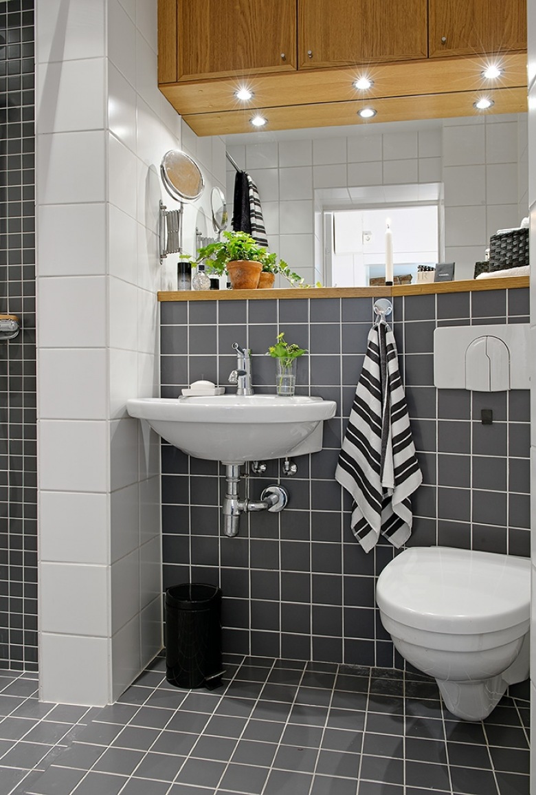 Czarne i białe kwadratowe płytki na scianie w małej łazience z drewnianymi półkami i szafkami (25904)