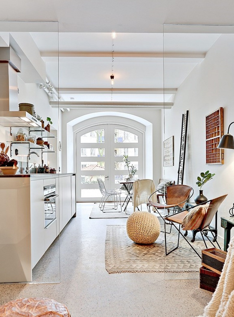 Lekka aranżacja otwartej przestrzeni małego mieszkania w bieli i brązach z metalowymi fotelami z wyplatanymi siedziskami (28086)