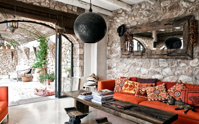 Kamienne ściany,drewniane lustro rustykalne,czarna lampa marokańska i czerwona kanapa z orientalnymi poduszkami (25389)
