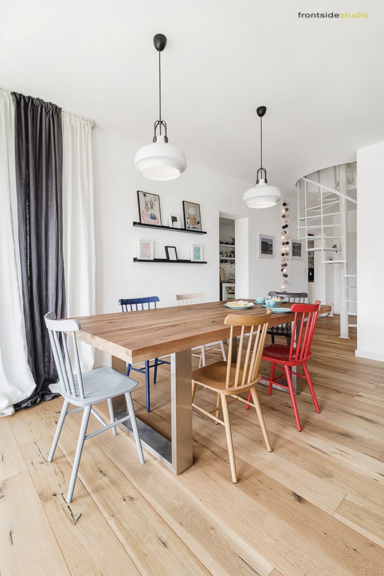 Prosta i funkcjonalna aranżacja jadalni, która idealnie wpisuje się w koncepcję aranżacji całego domu. Skandynawski styl podkreślony wyborem drewnianych mebli został lekko urozmaicony różnobarwnymi krzesłami przy pięknym stole. Delikatne ozdobny na wąskich półeczkach na ścianie w subtelny sposób dekorują...
