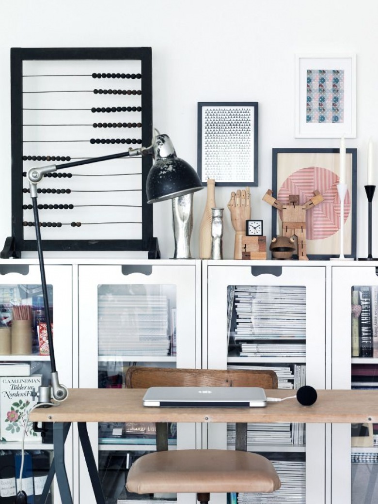 Białe przeszklone witryny na podłodze,metalowe biurko z drewnianym blatem,industrialne krzesło biurkowe i czarna lamka przypieta do blatu biurka (26148)