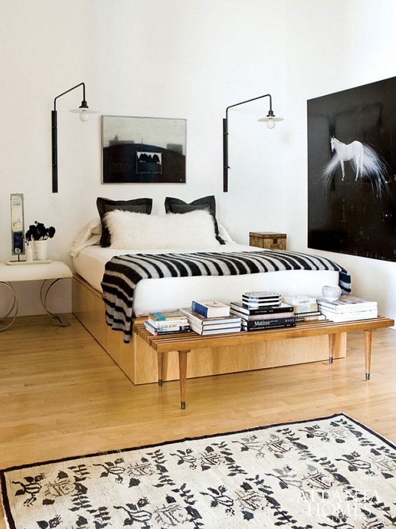 Czarne kinkiety, pościel  i fotografie w białej sypialni z drewnianym łóżkiem (20894)