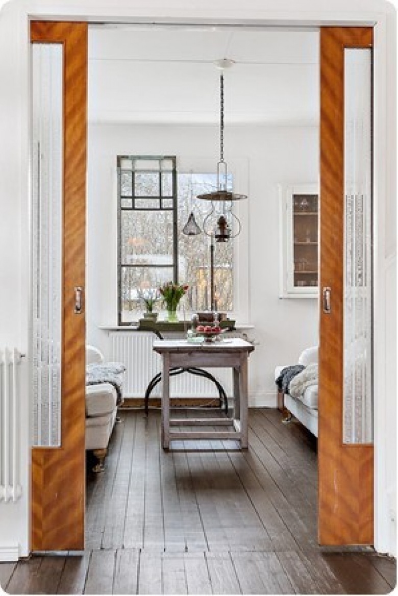 Miodowe drewniane drzwi przesuwne w jadalni ze stołem vintage i rustykalną lampą z metalu i szkła (27870)
