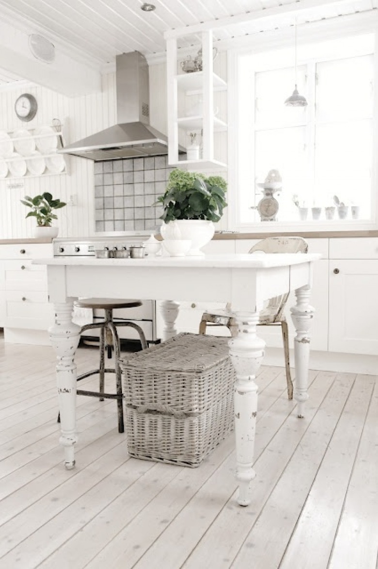 Biała kuchnia z podłogą z naturalnego drewna,biały stół na toczonych nogach z wiklinowym koszem (27040)