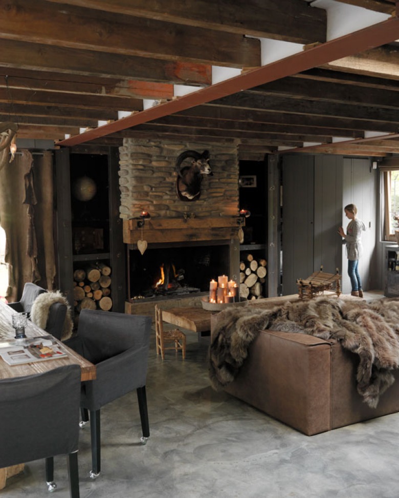 Drewno i naturalny kamień przy kominku w rustykalnym salonie ze skórzaną sofą,futrzakami i betonową podłogą (27676)