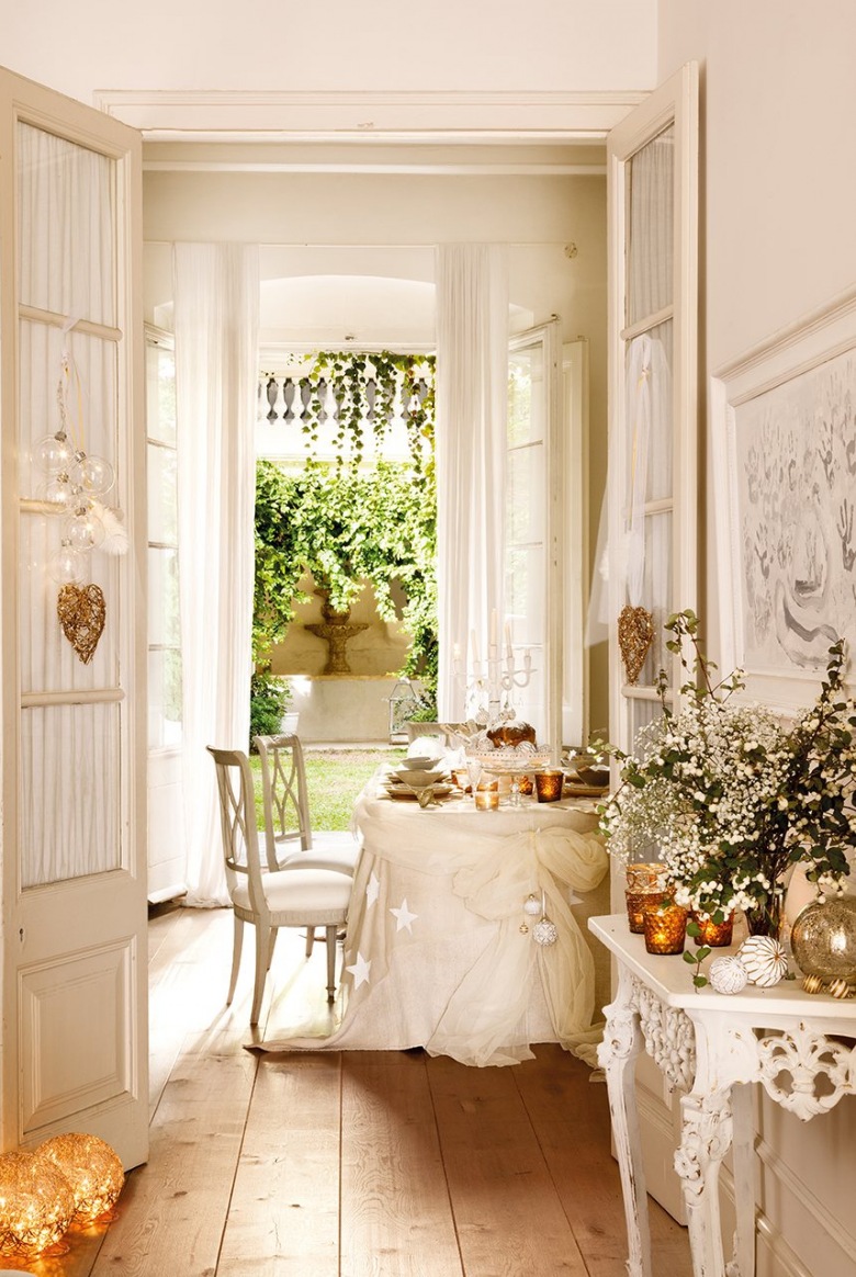 Szerokie deski z naturalnego drewna na podłodze,białe francuskie krzesła,białe drzwi z dekoracyjna firanką i świąteczne dekoracje w stylowej  jadalni (27359)