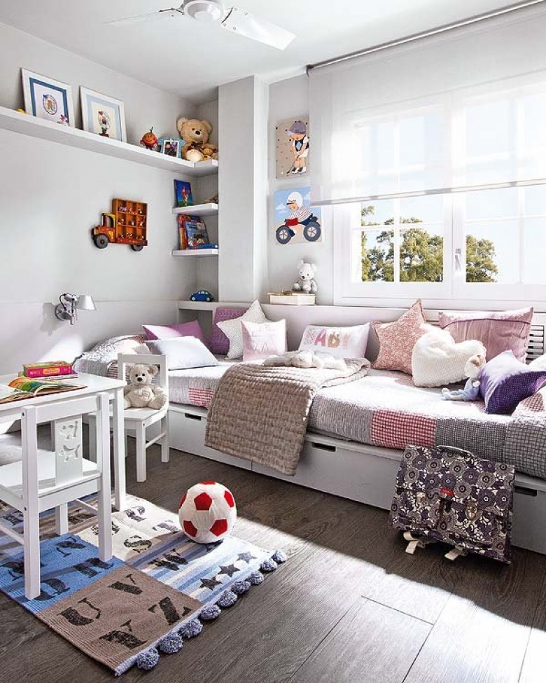 Białe łóżko z szufladami, różowymi i fioletowymi poduszkami w pokoju dziecięcym z półkami i białymi mebelkami (25527)