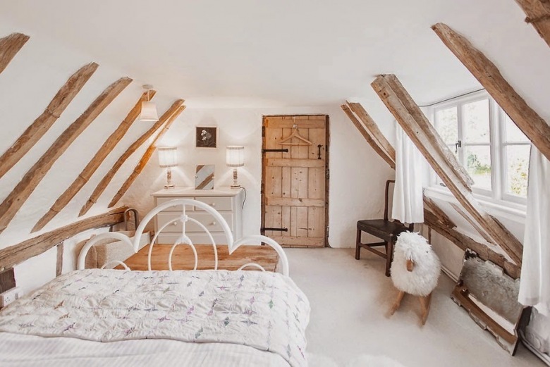 Drewniane wiejskie wrota w aranżacji sypialni z białym kutym łóżkiem na poddaszu (24933)