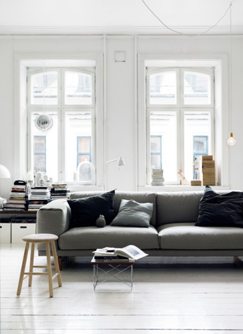 Szara kanapa z czarnymi poduszkami w białym salonie (20317)