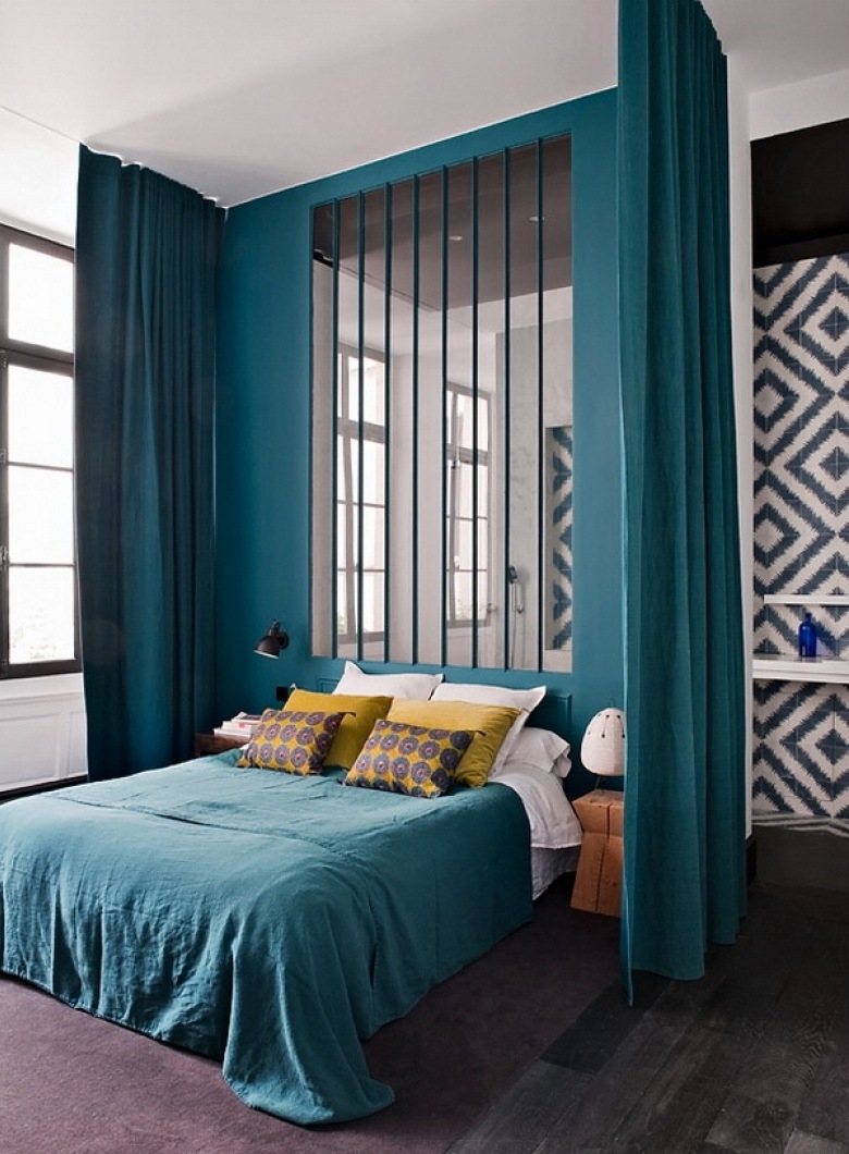 Ciemno-turkusowe zasłony i sciana z lustrzanymi listwami w aranżacji nowoczesnej sypialni z turkusową narzutą,żółtymi poduszkami i grafitową podłogą z desek (26191)