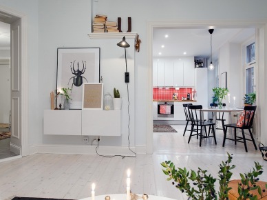 Otwarty salon z jadalnią i kuchnią w stylu skandynawskim z wiszącą szafką z grafikami i biała podłogą z desek (27065)