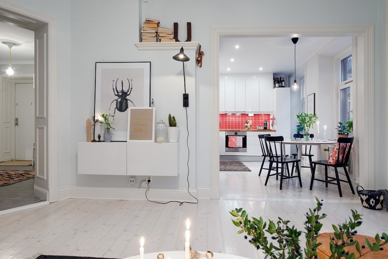 Otwarty salon z jadalnią i kuchnią w stylu skandynawskim z wiszącą szafką z grafikami i biała podłogą z desek (27065)
