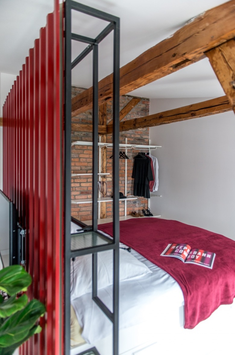 W sypialni jeden fragment ściany został wyłożony czerwonymi cegłami. Razem z drewnianymi belkami tworzą one oryginalny i naturalny efekt....