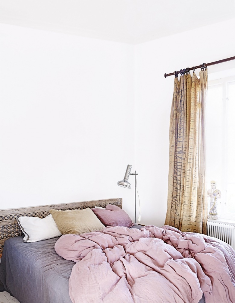 Lniane zasłony na drążkowym karniszu w białej sypialnu z marokańskim drewnianym łóżkiem i szaro-wrzosową pościelą (27396)