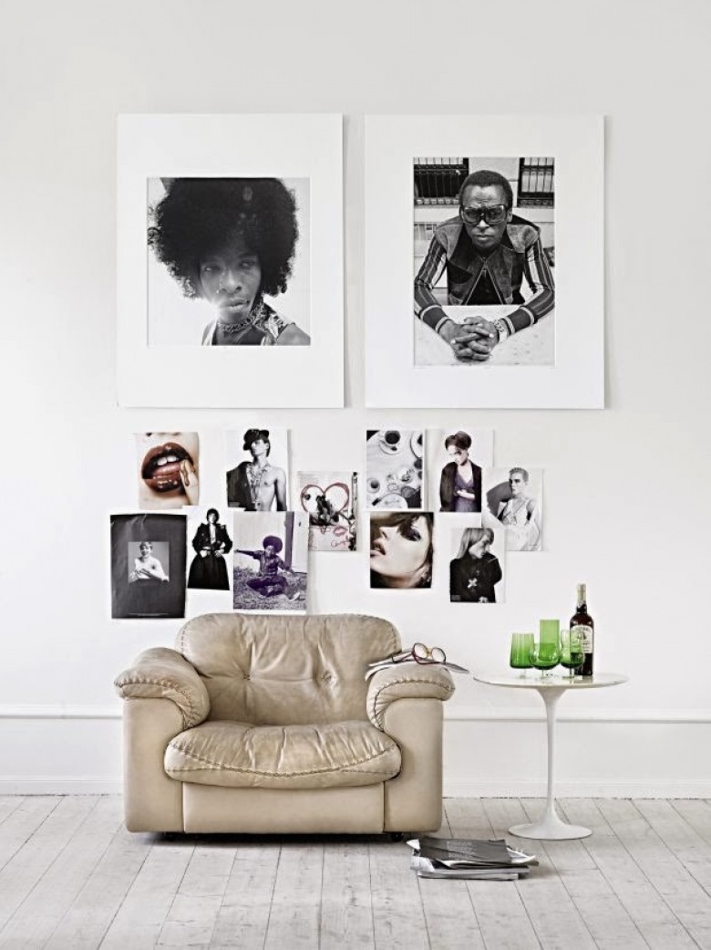 Czarno-białe fotografie w antyramach na białej ścianie w nowoczesnej aranżacji ze skórzanym fotelem i bialym okragłym stolikiem (24617)