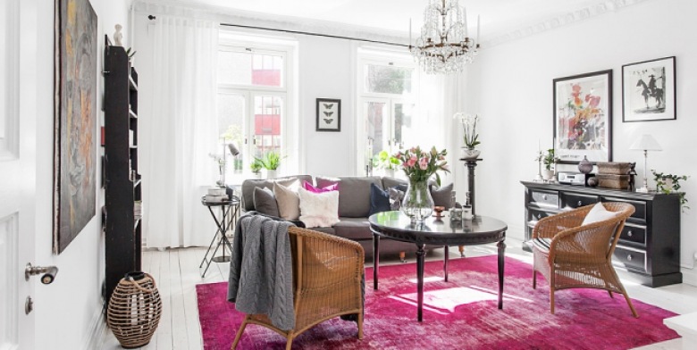 Eklekryczny salon z różowym dywanem i czarnym okrągłym stołem, wiklinowymi fotelami i skandynawskim lampionem (24854)