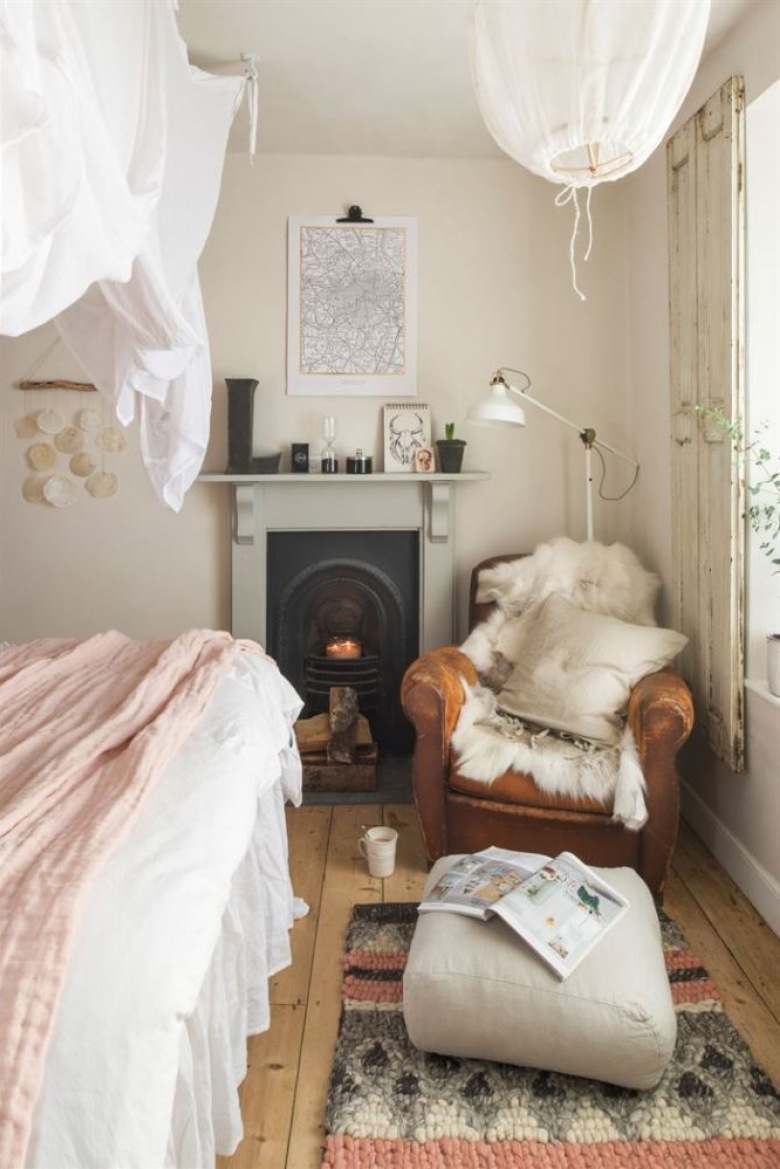 W sypialni jest wiele dodatków i tkanin, które podkreślają ciepły charakter wnętrza. Należą do nich m.in. materiałowy klosz od lampy wiszącej, miękki pled i poduszki na fotelu czy dekoracja z poduszek i pledów na...