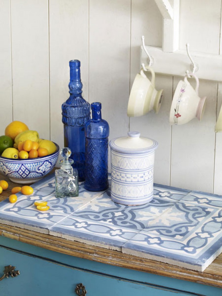 Śródziemnomorskie płytki w aranżacji kuchni z niebieska komodą i butelkami w kolorze indygo (23937)