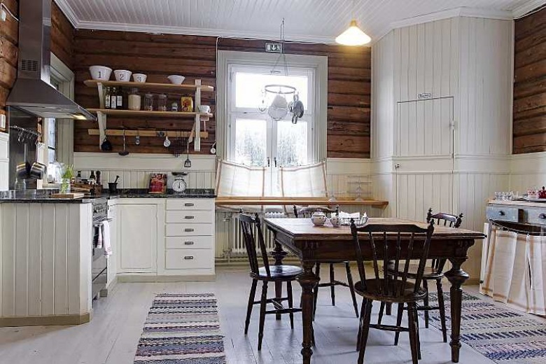Drewniane bałki na ścianie, białe drewniane panele w zabudowie kuchennej,podłoga z bielonych desek,rustykalny stół z krzesłami (27638)