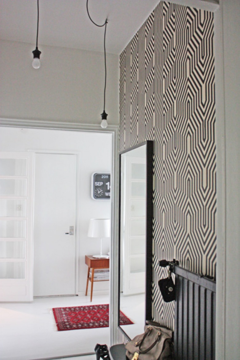 Biało-czarna graficzna tapeta na scianie w przedpokoju z czarnym prostokatnym lustrem i żarówkami na kablach (26081)