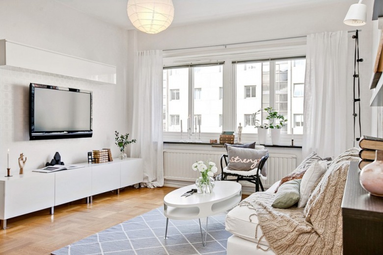 Białe szafki TV ,biały owalny stolik kawowy,białe zasłony i sofa w salonie,girlanda z żarówkami przy oknie w salonie (28485)