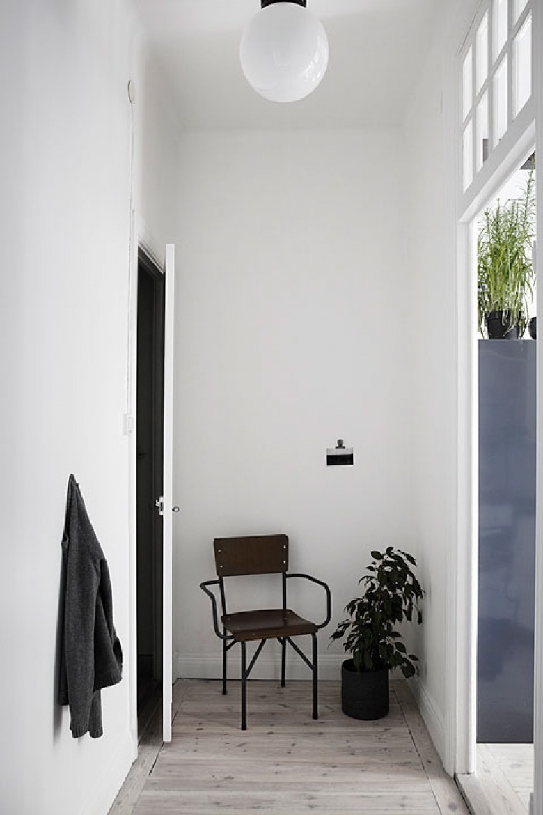 Industrialne metalowe krzesło,białe ściany,czarne drzwi w otwartym przedpokoju w mieszkaniu (26447)