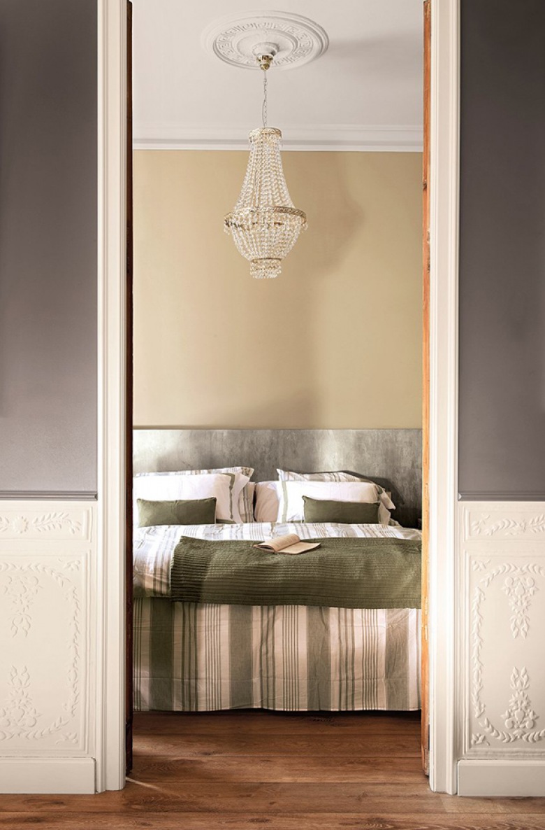 Szaro-beżowe ściany , kryształowy żyrandol i prosta dekoracja łóżka w sypialni (22188)