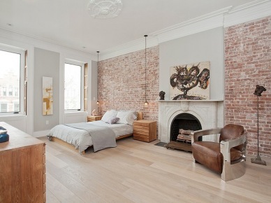 Desingerski fotel ze skóry i metalu w aranżacji sypialni ze ścianami z czerwonej cegły (24430)