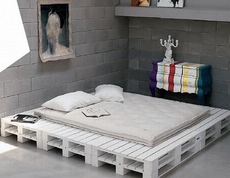 Podstawa i ramy łóżka z białych drewnianych palet w awangardowej sypialni z betonowymi scianami i kolorową komodą (25331)