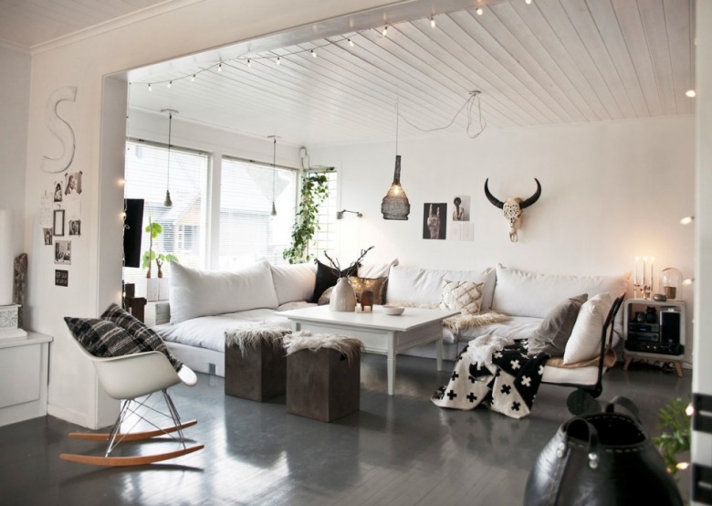 Biały otwarty salon z grafitową podłogą,girlandą z żarówkami, białymi sofami i fotelem na płozach (47885)