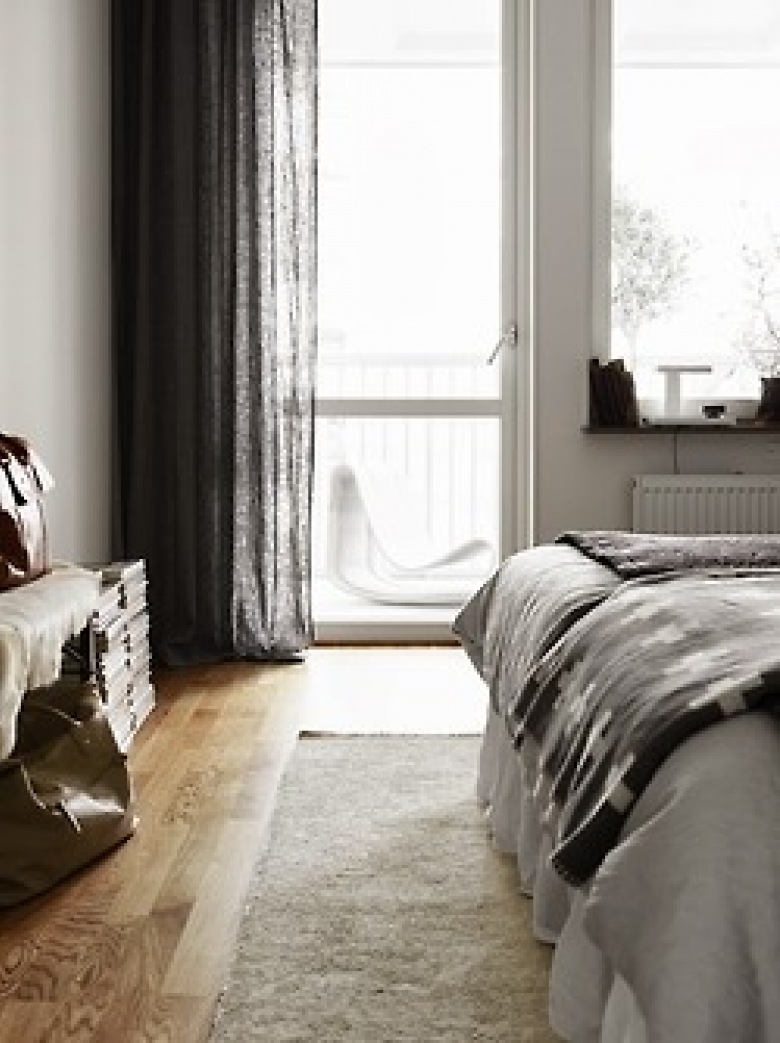 Ciemnoszare lniane zasłony,czarna narzuta z białymi szwedzkimi wzorami,biały futrzak na podłodze w dekoracji sypialni (25830)