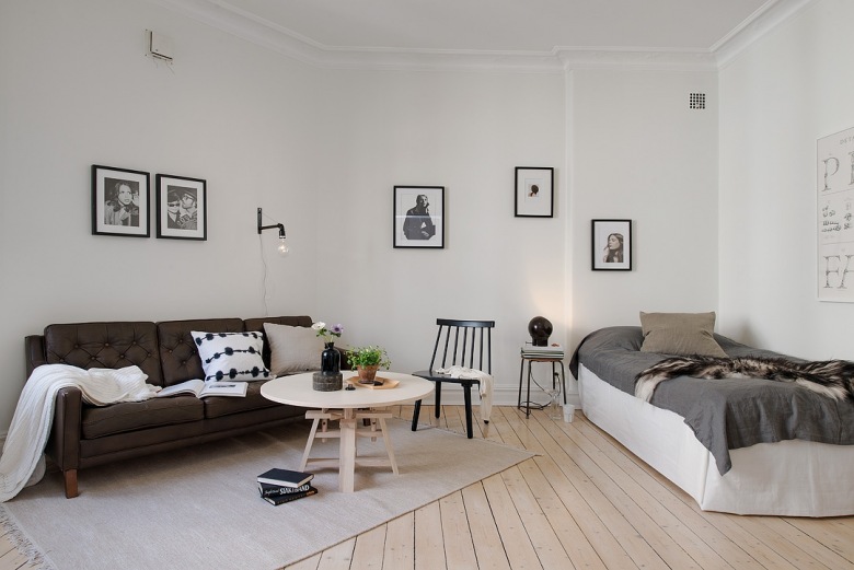 Brązowa sofa,w salonie z łóżkiem  w biało-szarych kolorach (22611)