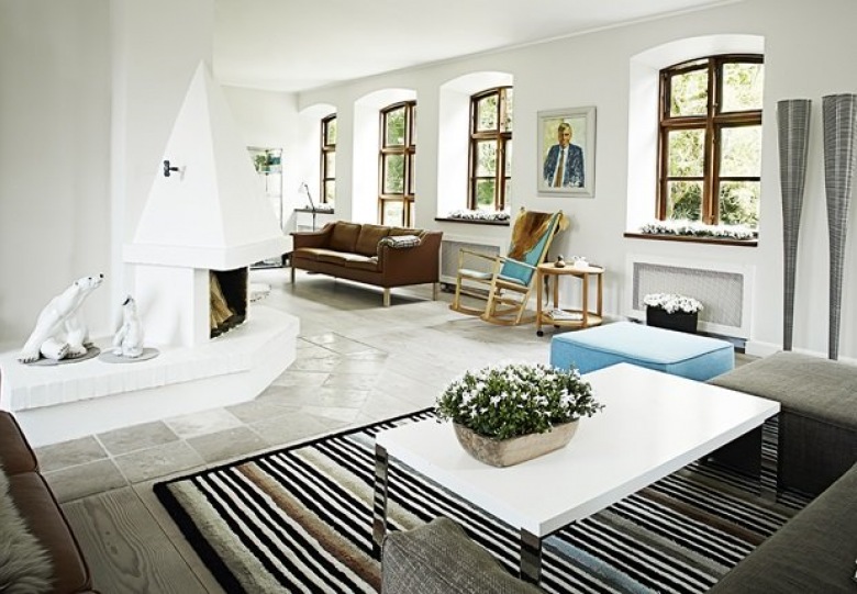 Biały salon z kominkiem,kamienną nowoczesna podłogą,skórzaną sofą i nowoczesnym stolikiem na pasiastym dywanie (25038)