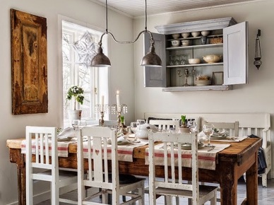 Miodowy drewniany stół z drewna w stylu rustykalnym,skandynawskie białe i patynowane krzesła vintage,szara wisząca podwójna lampa z metalu i szara szafka z pólkami na ścianie w kuchni wiejskiej w stylu skandynawskim (27452)