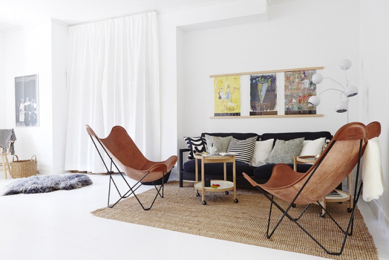 Beżowy dywan,czarno-białe poduszki,czarna sofa,brązowe fotele butterfly i drewniany stolik w aranżacji salonu z białą podłoga i ścianami (24653)