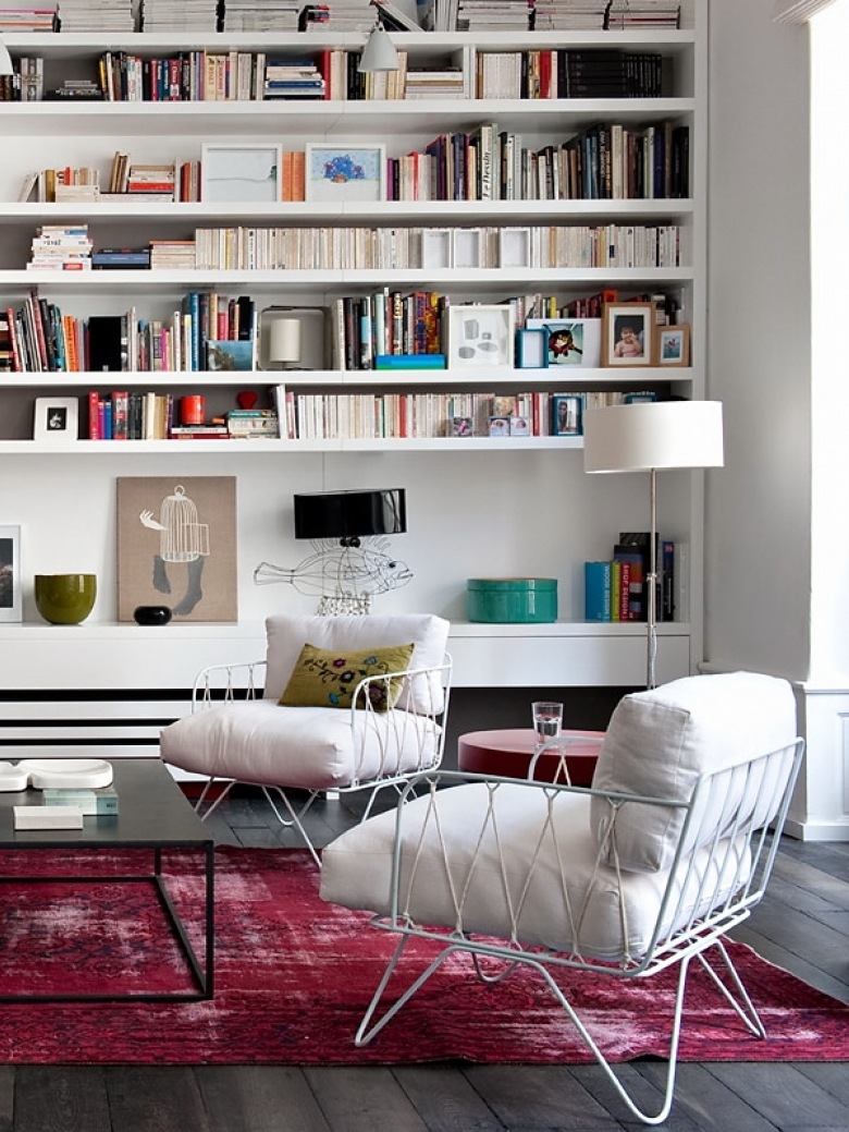 Różowy dywan vintage,biały nowoczesny fotel z metalowych pretów i z poduchami,białe półki na ścianie w salonie (26183)